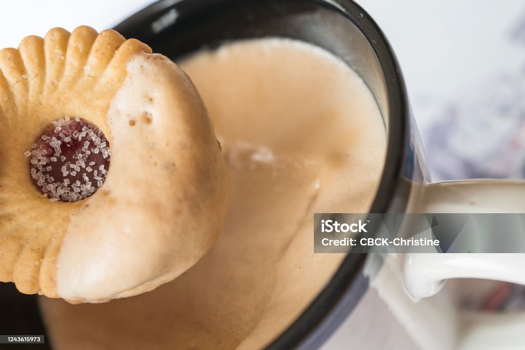 Sugared jam ring biscuit being dunked into frothy coffee in a mug Chocolate Dipped Stock Photo