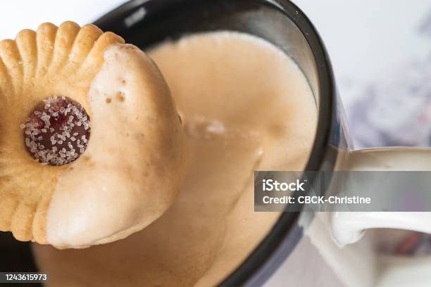 Sugared Jam Ring Biscuit Being Dunked Into Frothy Coffee In A Mug Stock Photo - Download Image Now
