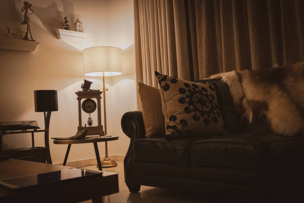 Close up photo of beige couch and lamp standing against a white wall in a modern flat.