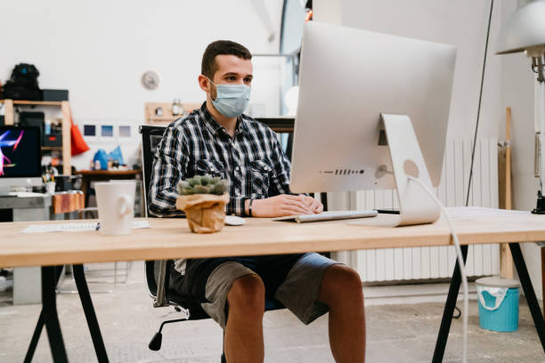 Young adult man is working at home with a desktop pc