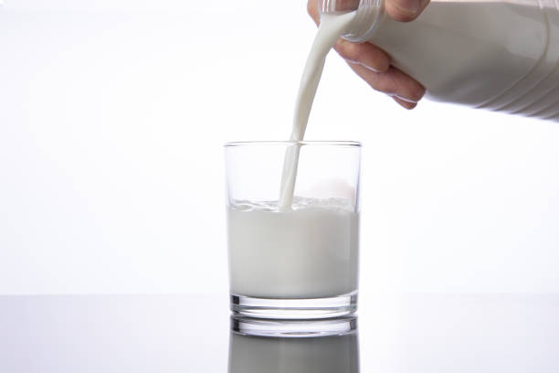 istock Pouring milk into a glass from bottle. white background 1243665148