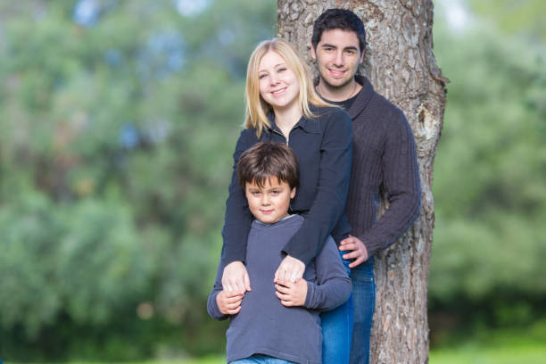 istock young couple and child hug and stand by a tree 1243676338