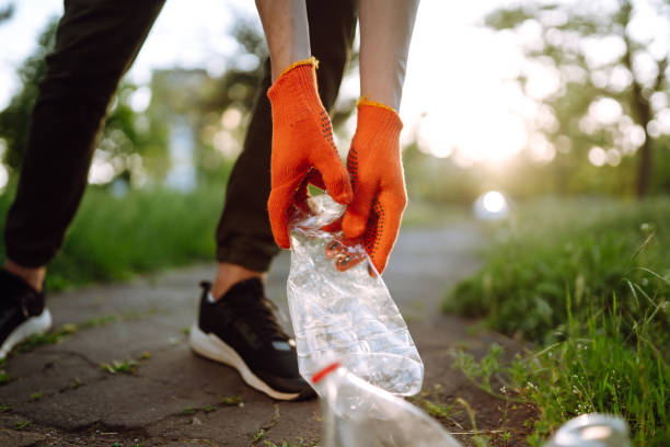 Men hand collects plastic trash for cleaning in the park.
