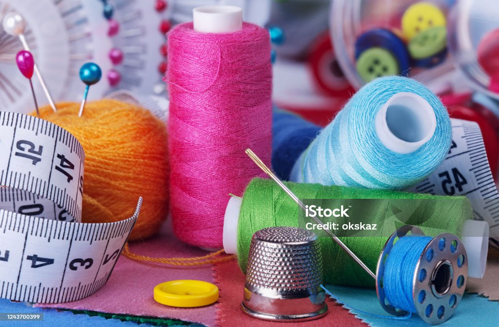 Multi-colored threads on bobbins, needles and pins, sewing kit. Sewing Stock Photo