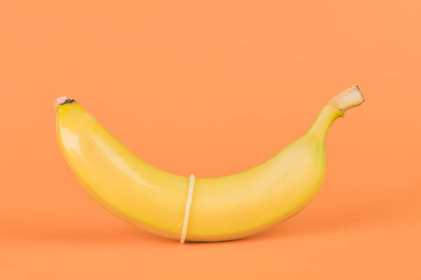 istock condom and a banana on orange background close-up. 1243721391