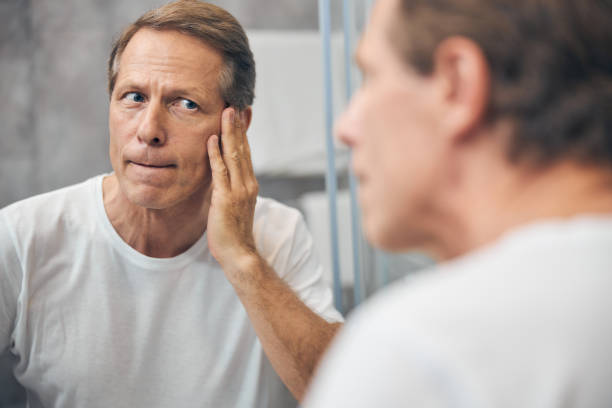 istock Man examining the skin on his face 1243729004