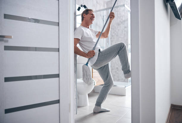 hombre de alto espíritu divirtiéndose durante la limpieza - one floor fotografías e imágenes de stock