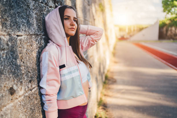istock Sporty woman posing while leaning on gray wall 1243751061