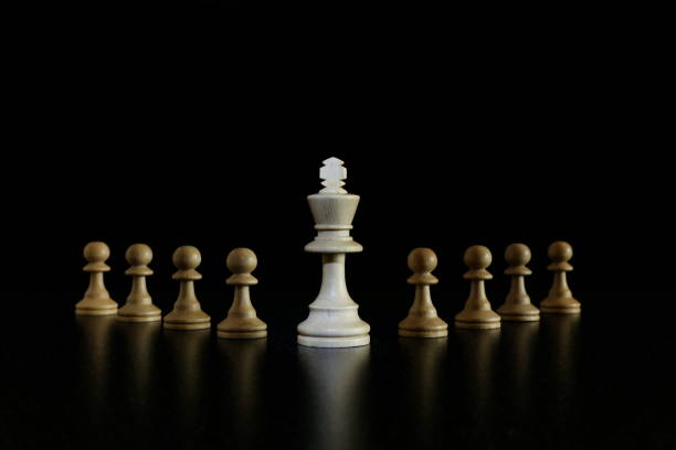 istock white king with a wedge of pawns on a black background. 1243764931