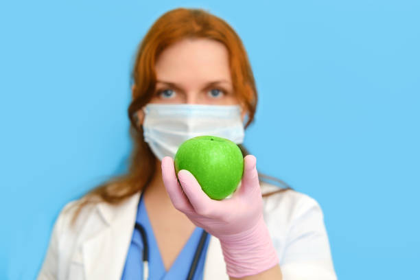 istock Doctor nutritionist hand with fruit on blue backgroun 1243787353