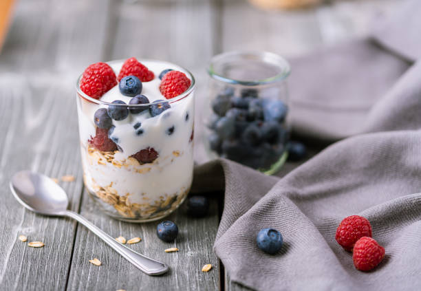 istock White yogurt in glass jar with blueberries on grey background. 1243788531