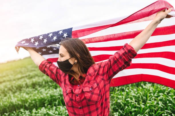 istock Girl wearing face mask holding US flag 1243801043