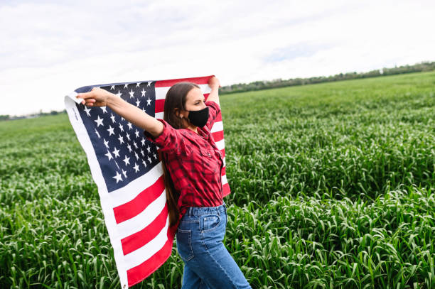 istock Girl wearing face mask holding US flag 1243801048