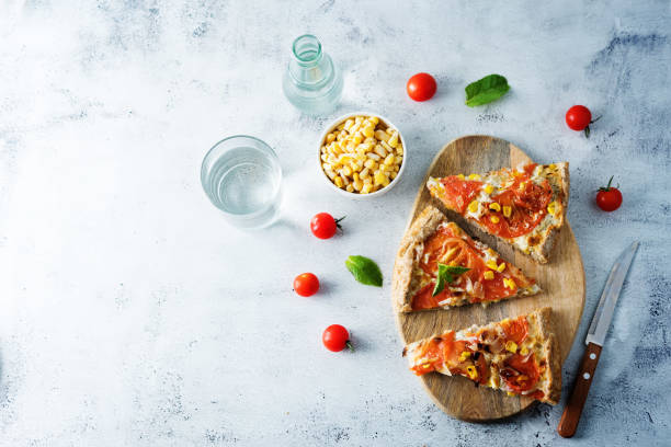 Pizza baked in the oven with tomato sauce and topped with mozzarella cheese, fried bacon, corn and oregano.