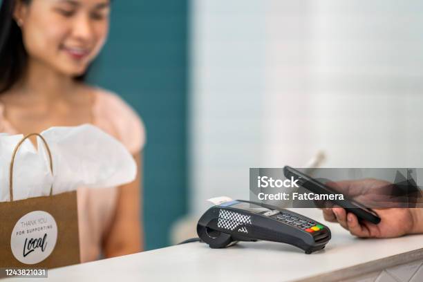 Customer Using Their Smart Phone To Pay In A Small Boutique Shop Stock Photo - Download Image Now