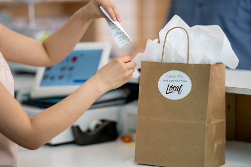 Retail worker placing debit receipt in a paper shopping bag  with a 