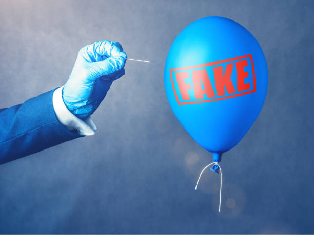 Concept of fake information. Blue balloon. Man hold needle directed to air balloon. Idea of disinformation and propaganda stock photo