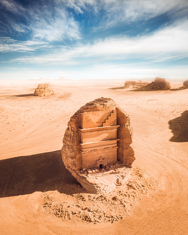 An ancient tomb and vast desert vista seen at Al-ʿUla in Al Madinah, Saudia Arabia as seen from the air with no visitors around.