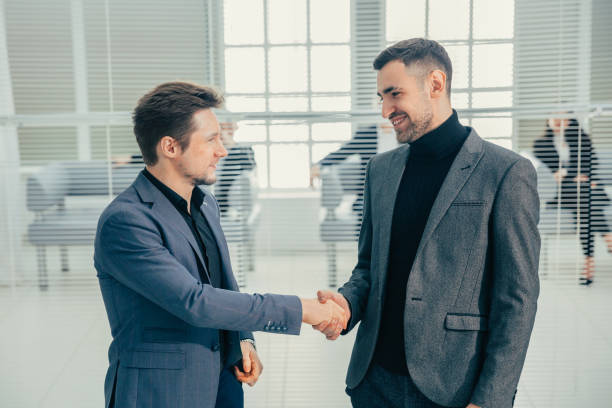 istock business people shaking hands standing in the office lobby 1243859198