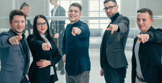 istock group of smiling employees pointing at you 1243859738