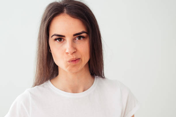 Skeptic and nervous young brunette on a light background frowns due to a problem. Negative person. Brown eyes.