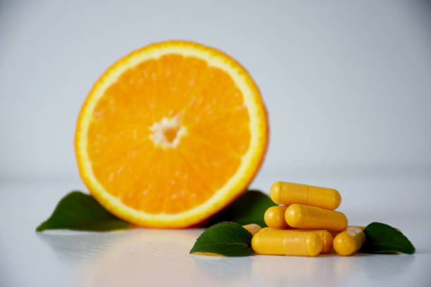 cápsulas de vitamin c con naranja - vitamin c fotografías e imágenes de stock