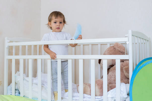 карантинная коронавирусная ковид-19 пандемия концепции. маленький милый ребенок находится в кроватке дома в безопасности, глядя серьезно в  - masc стоковые фото и изображения