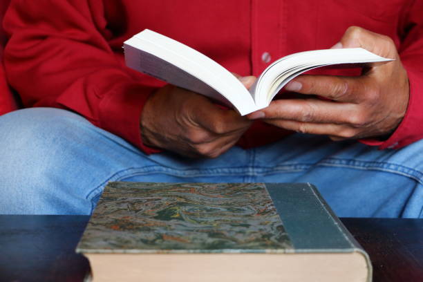 istock Man with a red shirt reading a book 1243910241