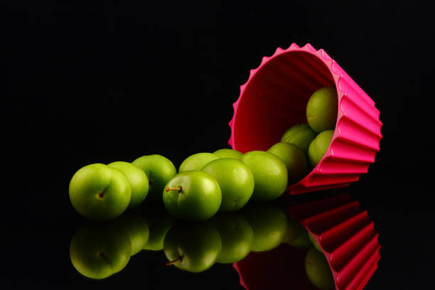 grüne pflaumen auf schwarzem hintergrund - grape heart shape fruit bunch stock-fotos und bilder