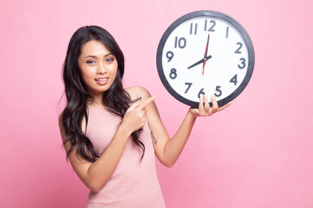 istock Young Asian woman point to a clock. 1243916065