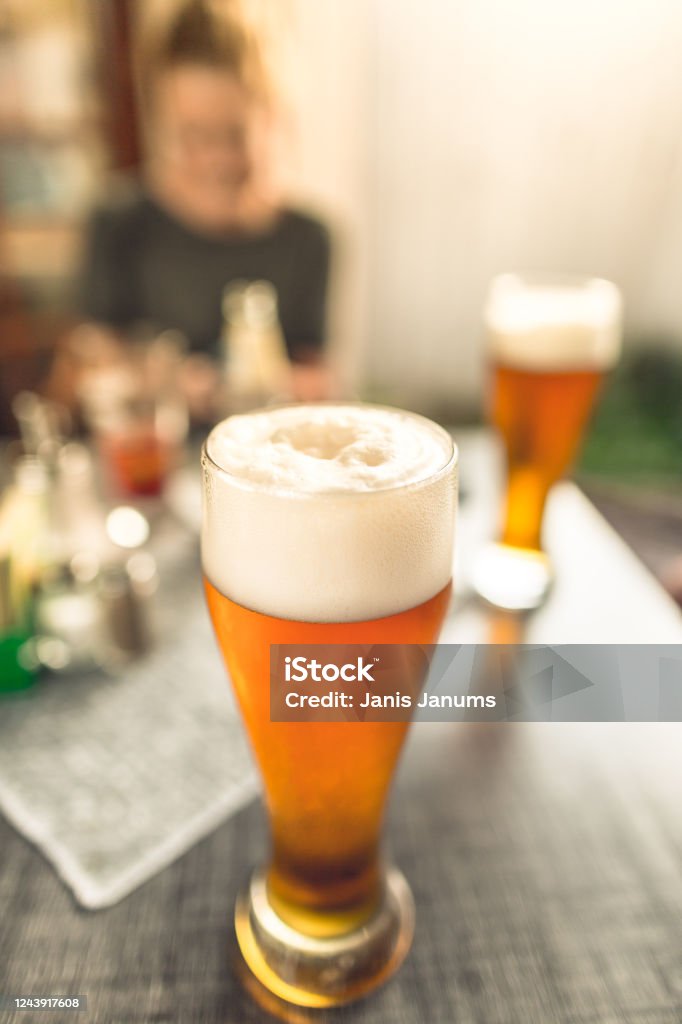 Glass of beer with large white foam in a pub Real glass of beer with large white foam seen in pub Beer Tap Stock Photo