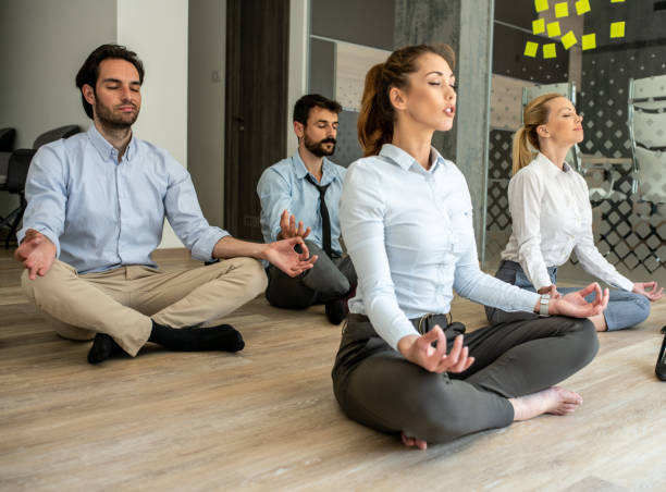 meditating at work - yoga meditating business group of people imagens e fotografias de stock