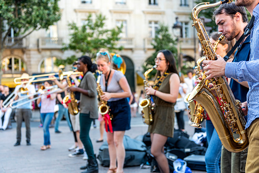 Paris, France - July 7, 2016: The bare brass band busking at Paris, France (Saint-Michel District). Young boys and girls are earning money by using classic musical instruments (trombone, saxophone, oboe, drums) in street of Paris. They are street musicians.