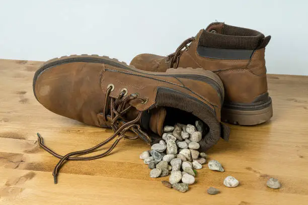 a shoe full of gravel overturned on a wooden surface