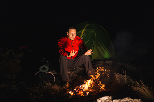Man warming up during his hiking adventure near a camp fire
