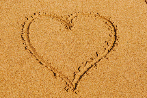 Heart on the beach against sky ocean background.