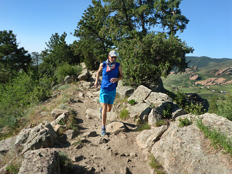 Winding through sandstone cliffs and boulders, a man trail runs in the morning on the Dakota Ridge Trail in Matthews/Winters Park in the Front Range Rocky Mountains, Morrison, Colorado.