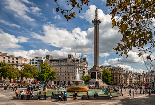 London / UK - September 15, 2018: People enjoy the sunshine in Trafalgar Square. Nelson's Column dominates the picture.