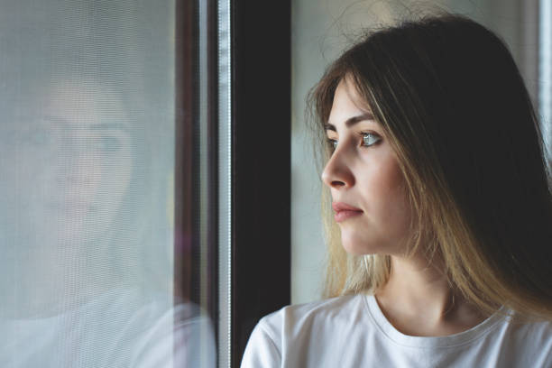 istock unhappy woman crying at the window 1244022523