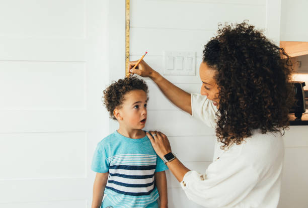 istock Mother Measuring Height of Son 1244033513