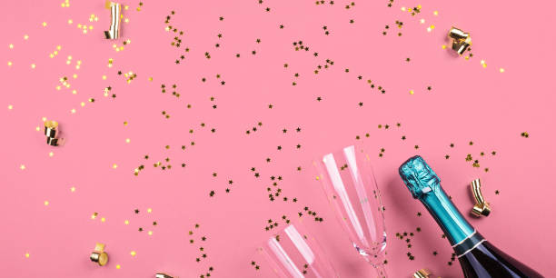 istock Champagne bottle and flutes on pink. Confetti 1244090127