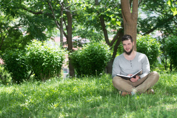 istock Young Muslim Guy Reading The Koran In Park 1244090345