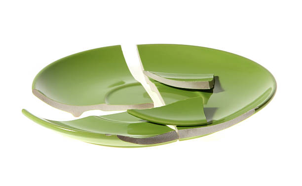 A broken ceramic green plate on a white background stock photo