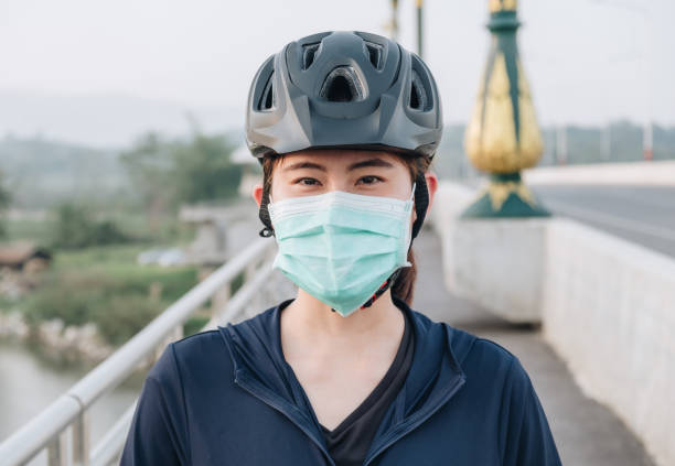 바이러스확산을 막기 위해 자전거를 타고 야외에서 마스크를 쓰고 있는 젊은 여성의 초상화. - mental health women asian ethnicity bicycle 뉴스 사진 이미지