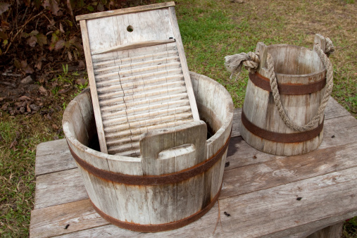 a washboard in a washtub with a water pail next to it .