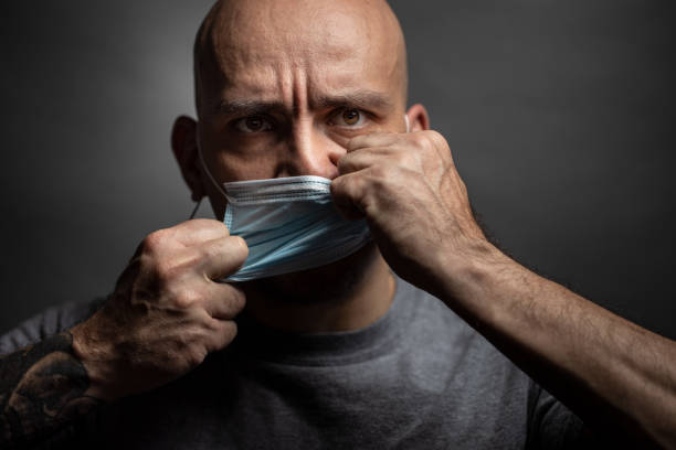 Man rips off a protective mask from his face. - fotografia de stock