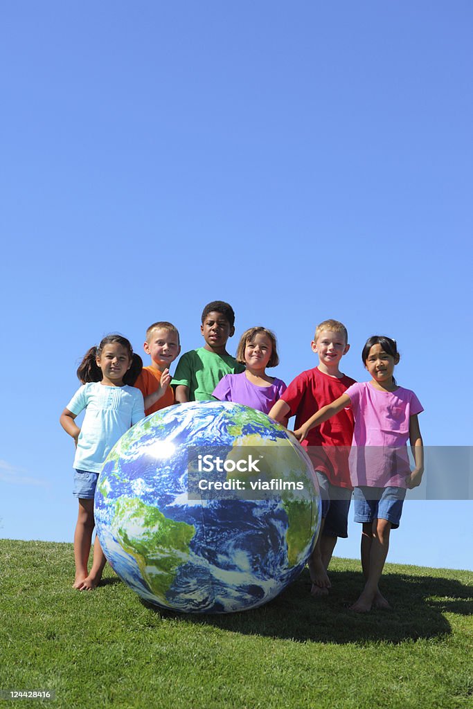 Portrait of multi-ethnic kids with large earth ball Portrait of multi-ethnic kids with large earth ball, on grass hill with blue sky Child Stock Photo