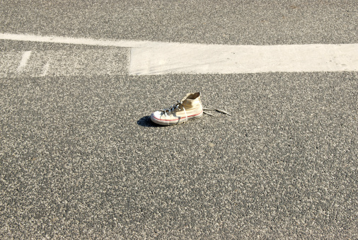 Lone canvas shoe on asphalt.