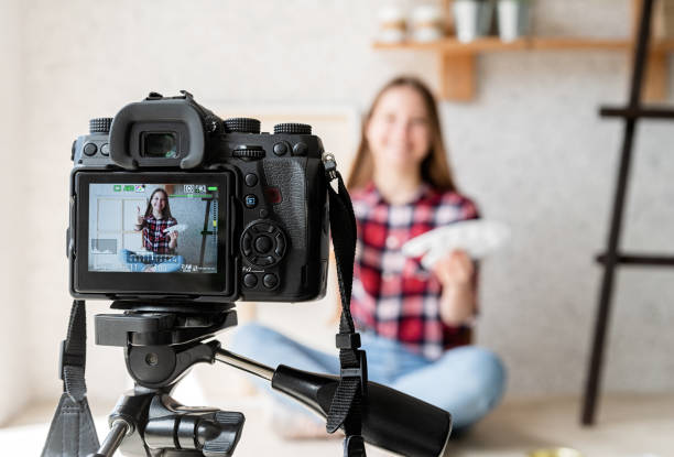 istock Woman making a video for her blog on art using a tripod mounted digital camera 1244391965