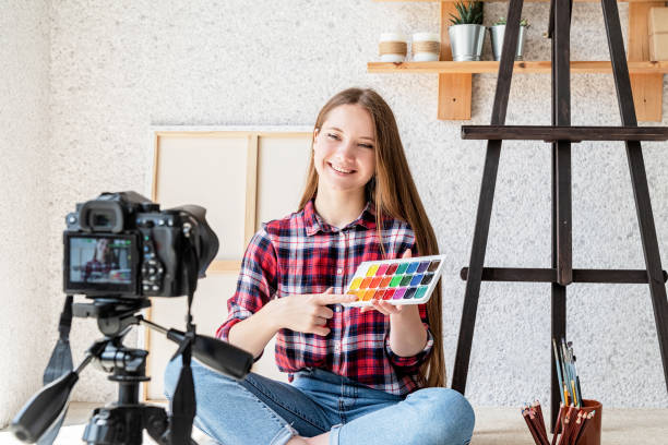 istock Woman making a video for her blog on art using a tripod mounted digital camera 1244393521